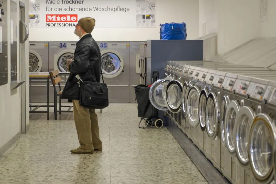 A man stands inside a Berlin laundromat, surrounded by Miele washing machines.
