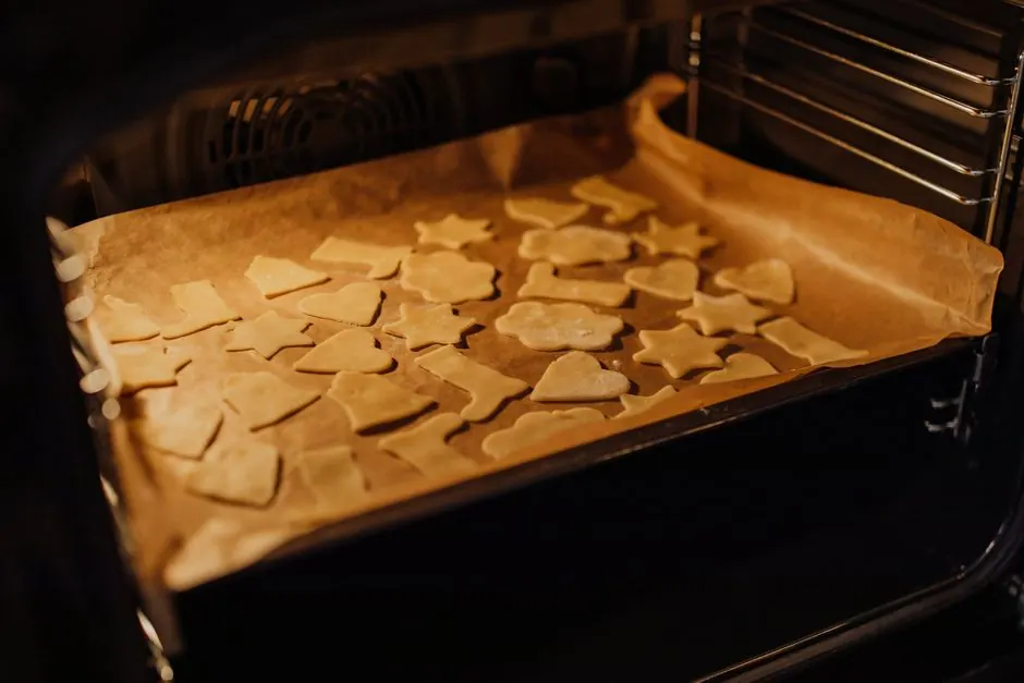 A tray of assorted shaped cookies baking in an oven, perfect for festive treats.